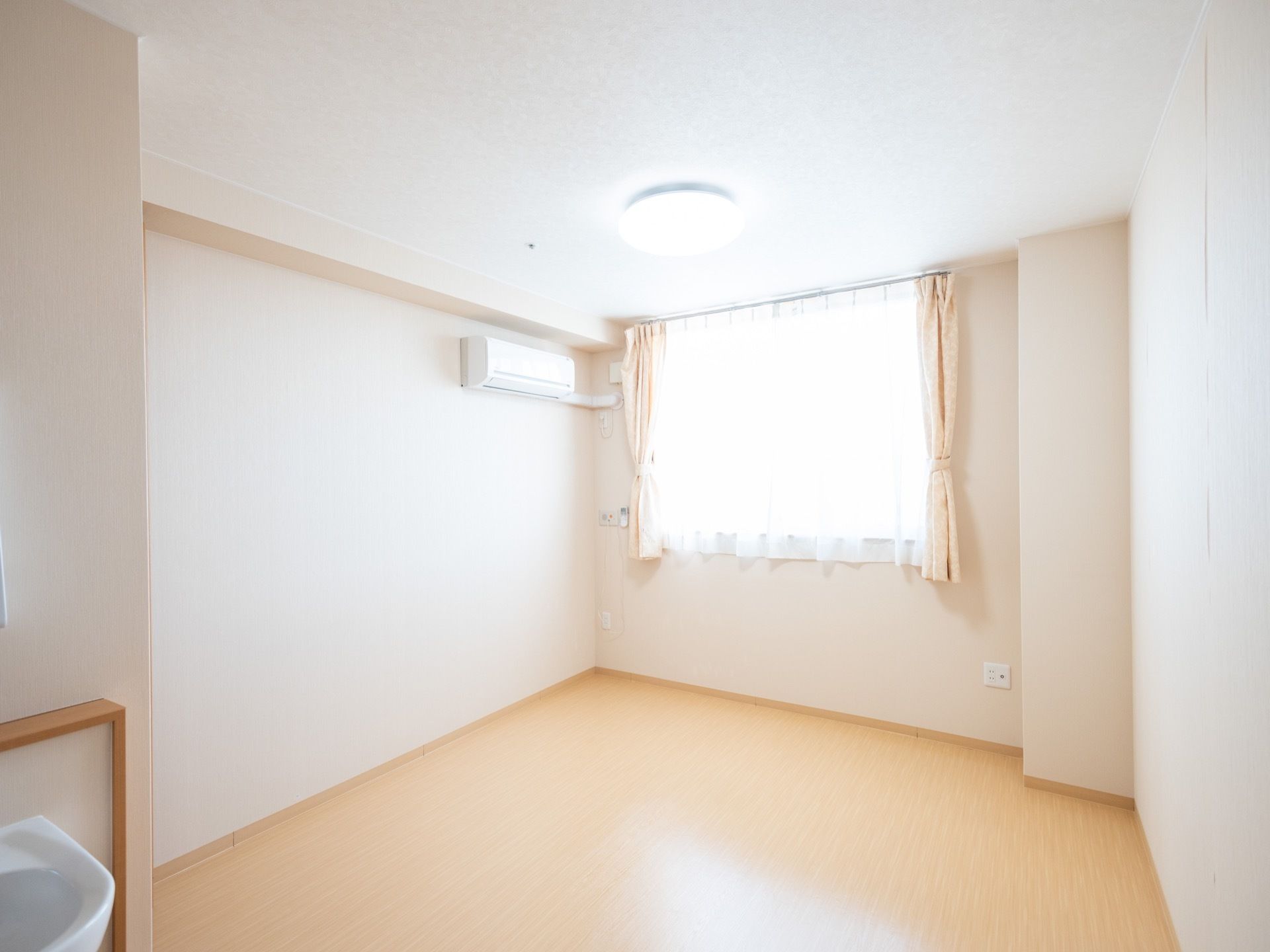 窓から陽光が差し込む明るい居室である。トイレ、洗面、収納、エアコンなど快適に過ごせる設備が整っている。