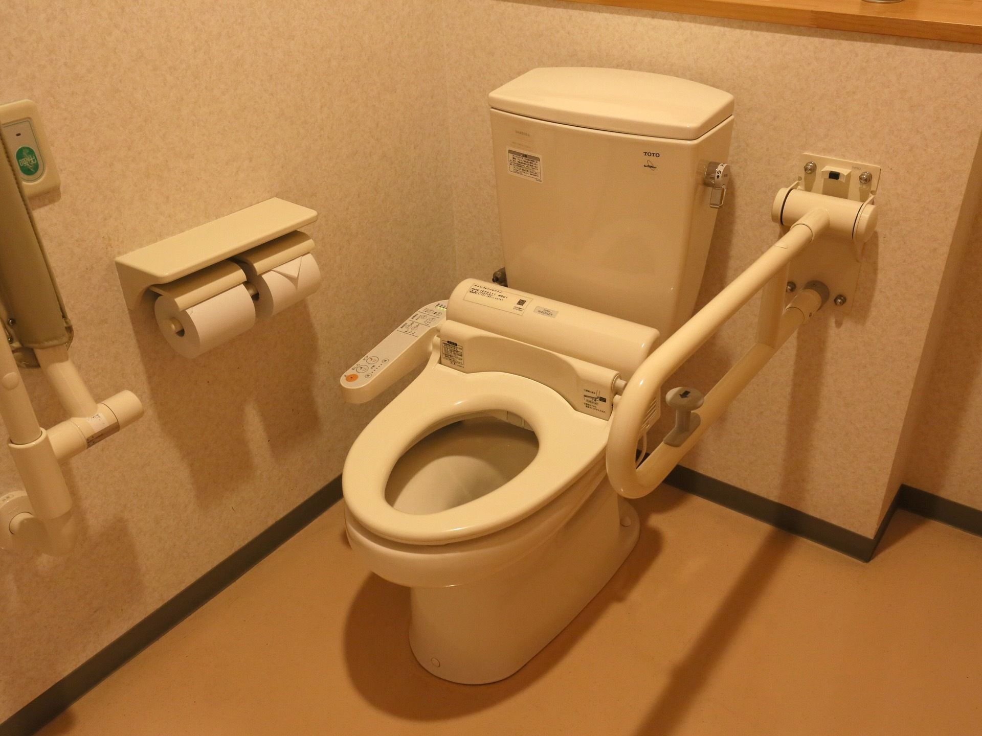 トイレは、水タンクがついた便器である。トイレットペーパーホルダーが２つ並んで設置されている。可動式の手すりが取り付けられている。