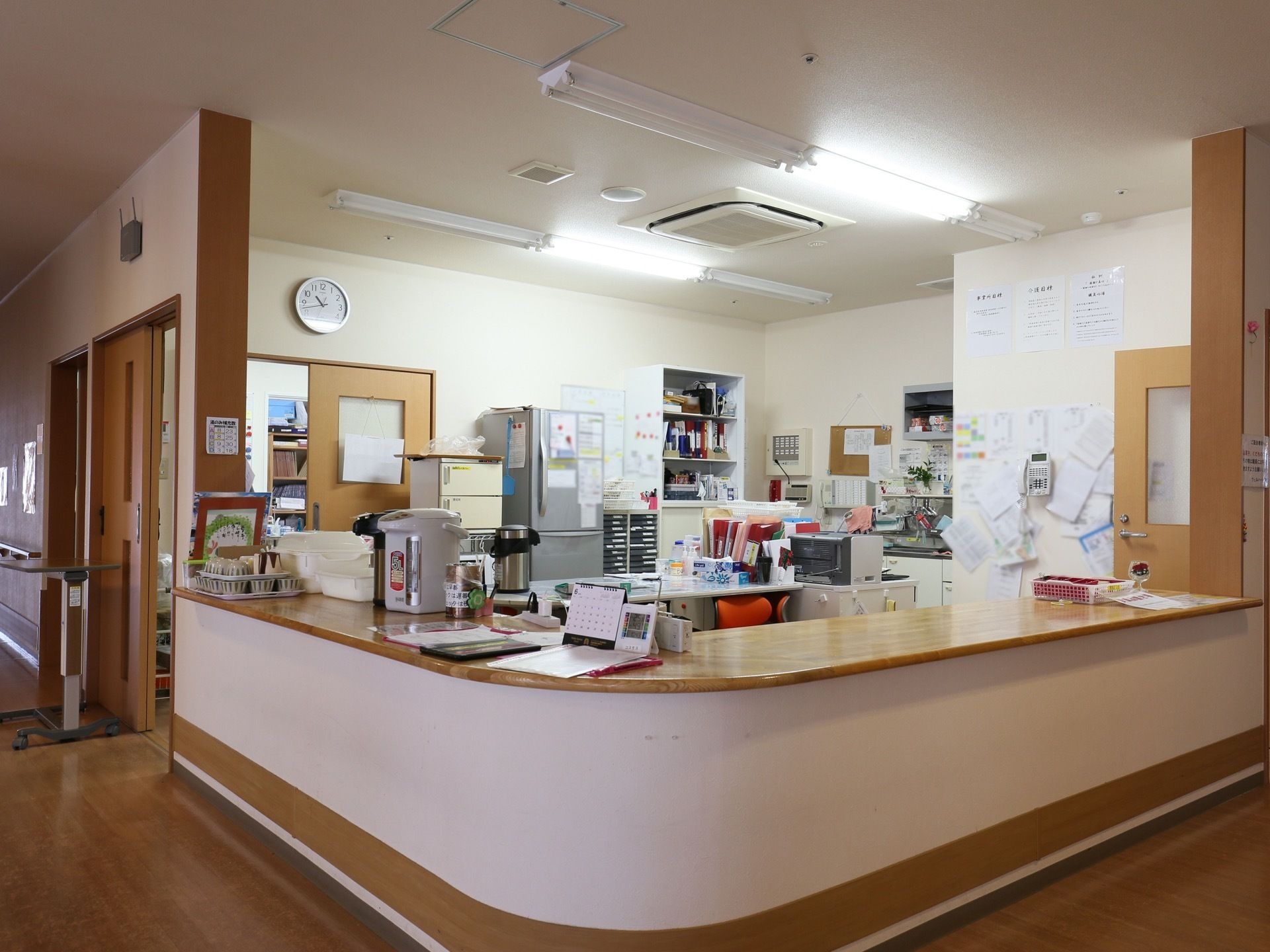 事務室はオープンな造りになっている。カウンターの上に、ポットや湯呑が置かれている。左右両側に入口がある。