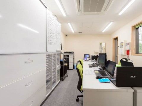 ホワイトボードで予定が管理されている、パソコンが置かれた職員室