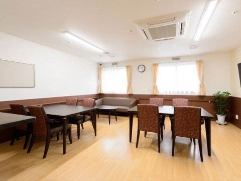 食堂には大きな窓がある。壁側のソファー後ろには手すりが取り付けられている。テーブルの周りには椅子が並べられている。