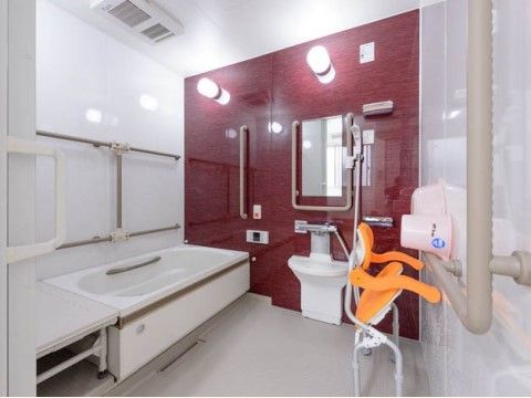 浴室の洗い場には介護用シャワーチェアーが用意されている。壁には手すりが設けられており、洗面器と手桶が置かれている。