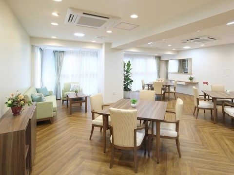 木製のテーブルセットが並んでいる広い空間がある。入居者様が食事をしたり、談笑を楽しむことができるリビングスペースとなっている。