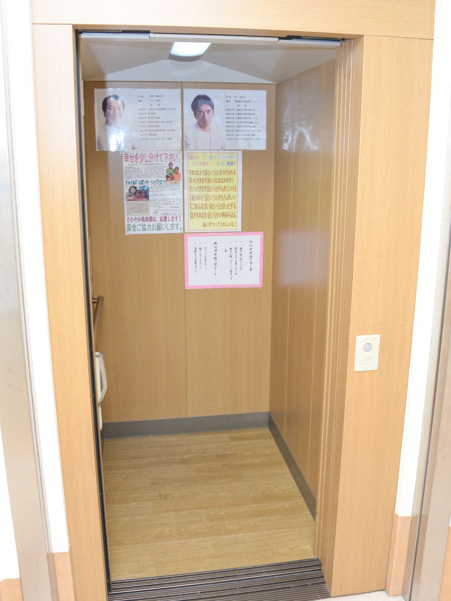 エレベーターは木目調で、中には手摺が備わっている。壁にはお知らせやスタッフの紹介などの掲示物が貼ってある。