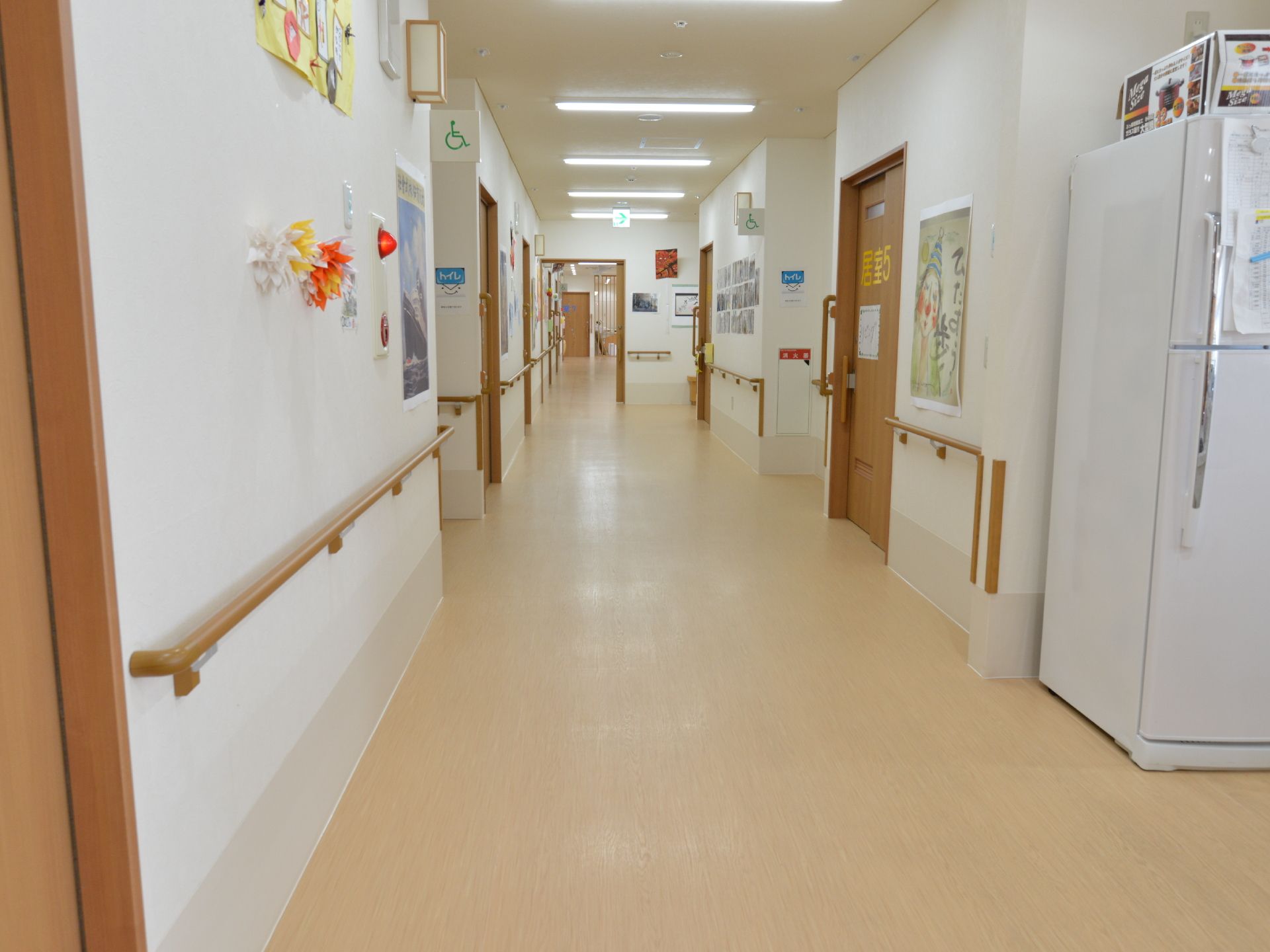 白い壁とベージュ系の床が明るく雰囲気の広々とした廊下。車椅子の方もストレスなく移動することができる。