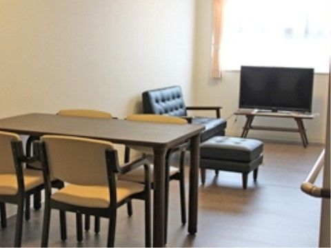 4人掛けのテーブルとソファが置かれた、テレビが見られる部屋