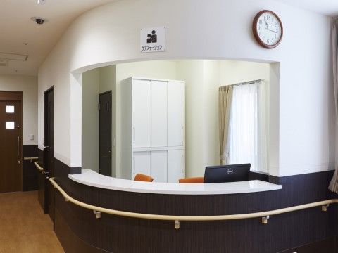 スタッフステーションは壁や家具が白いため清潔感がある。また時計があるので今何時か分かるようになっている他、手すりも設置されている。