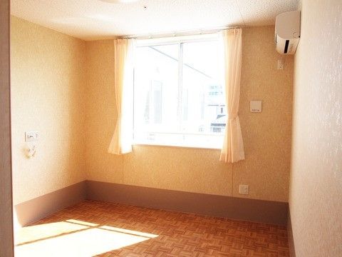 カーテンとエアコンが取り付けられた一人暮らし向きのワンルーム