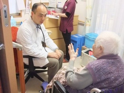車椅子に座った入居者様の話を真剣な面持ちで聞く医師と看護師