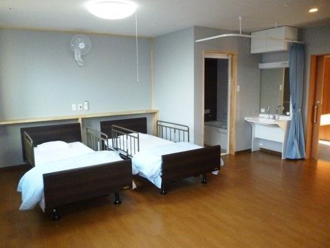 2つのベッドの上の壁に、扇風機が備え付けられた広い部屋