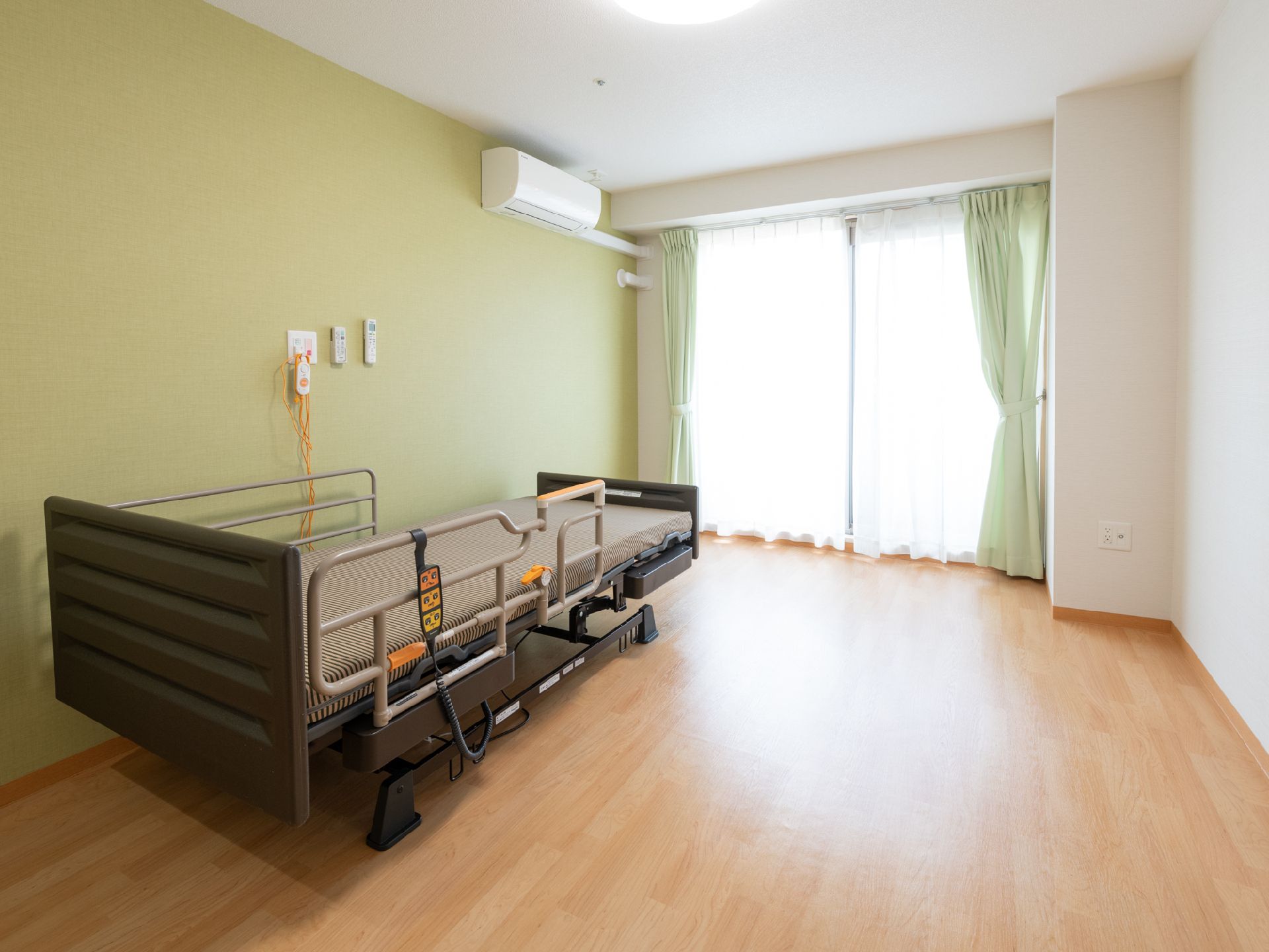 呼び出しボタン付きの介助ベッドが置かれた、一人暮らし向きの部屋