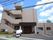 住宅街の道路沿いに施設がある。施設の正面には、玄関があり、屋根がついている。2台とめられる駐車場もある。