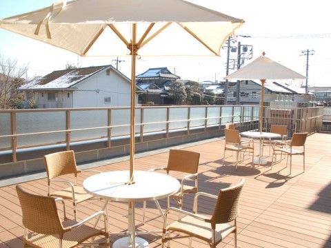 パラソル付きの4人用テーブルが2つ並べられた外のテラス