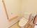 明るく清潔な個室に、温水洗浄便座付きのトイレが設置されている。壁には縦型の手すり、便器の左には、可動式の手すりが取り付けられている。
