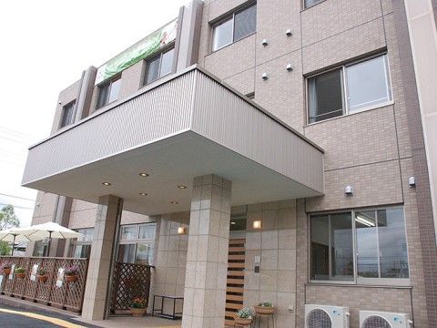 玄関横にパラソル付きの席があるテラスが見える、３階建ての施設外観