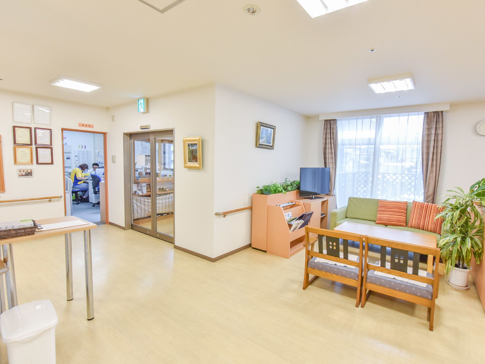 自動ドアの入り口を入って左手に入るとテーブルやソファが置かれている。窓からは光が差し込み観葉植物などが置かれている。