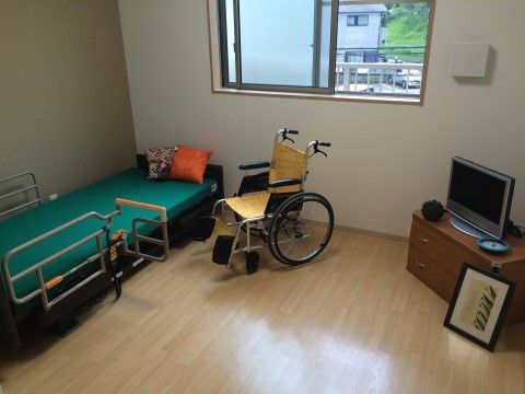 車椅子への乗り換えがしやすいベッドとテレビが置かれたワンルーム