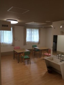 2人用テーブルが2つと、鏡付きの洗面台が置かれたフロア