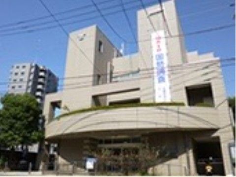 グレー調で現代的なデザインの建物。玄関ポーチから入口まで、スロープや手すりがある。道路と敷地の境には進入防止のポールが設置されている。