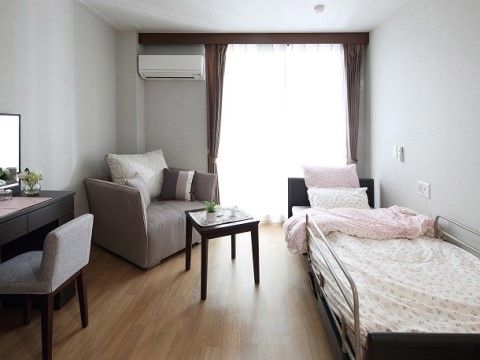 ソファとベッド、テーブル、化粧台が置かれたエアコン付きの部屋