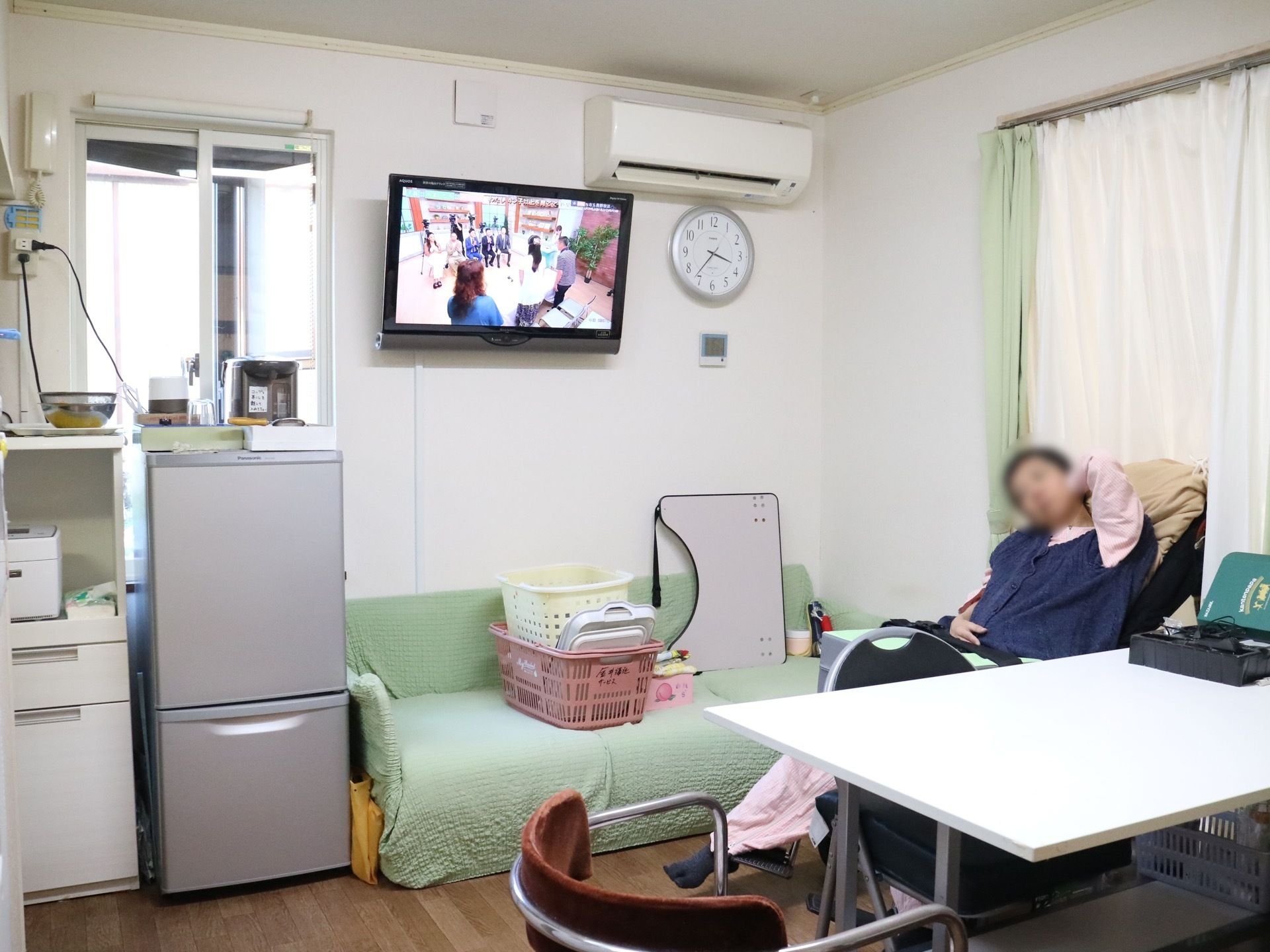 入居者様が普段から集まるリビング。壁には壁掛け式のテレビがあり、その右上にはエアコンが設置されている。