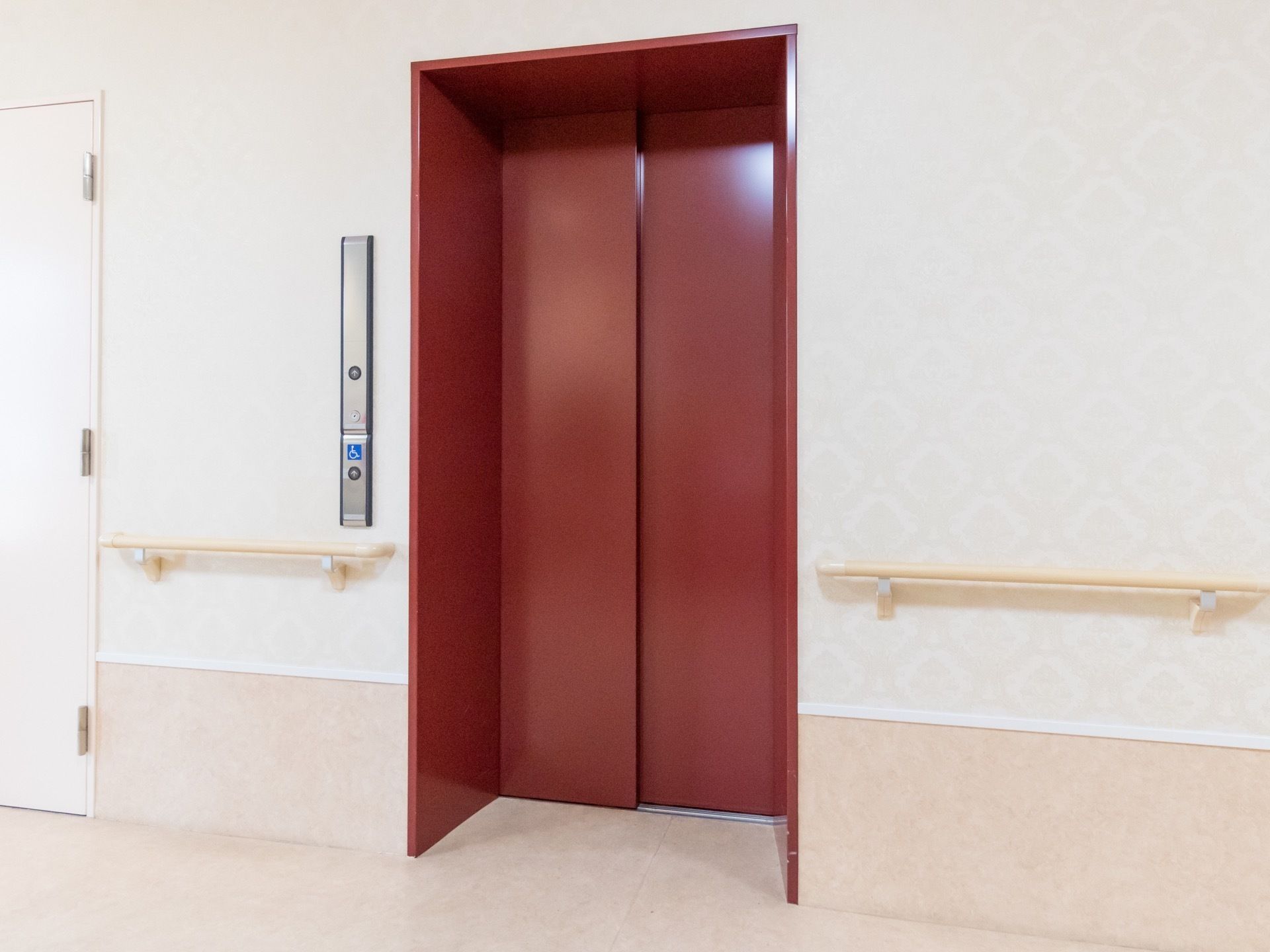 エレベーターは周囲の内装に合わせ、濃いローズ色にして統一感を出している。周りは広く空けて、安全に乗降できるように配慮されている。