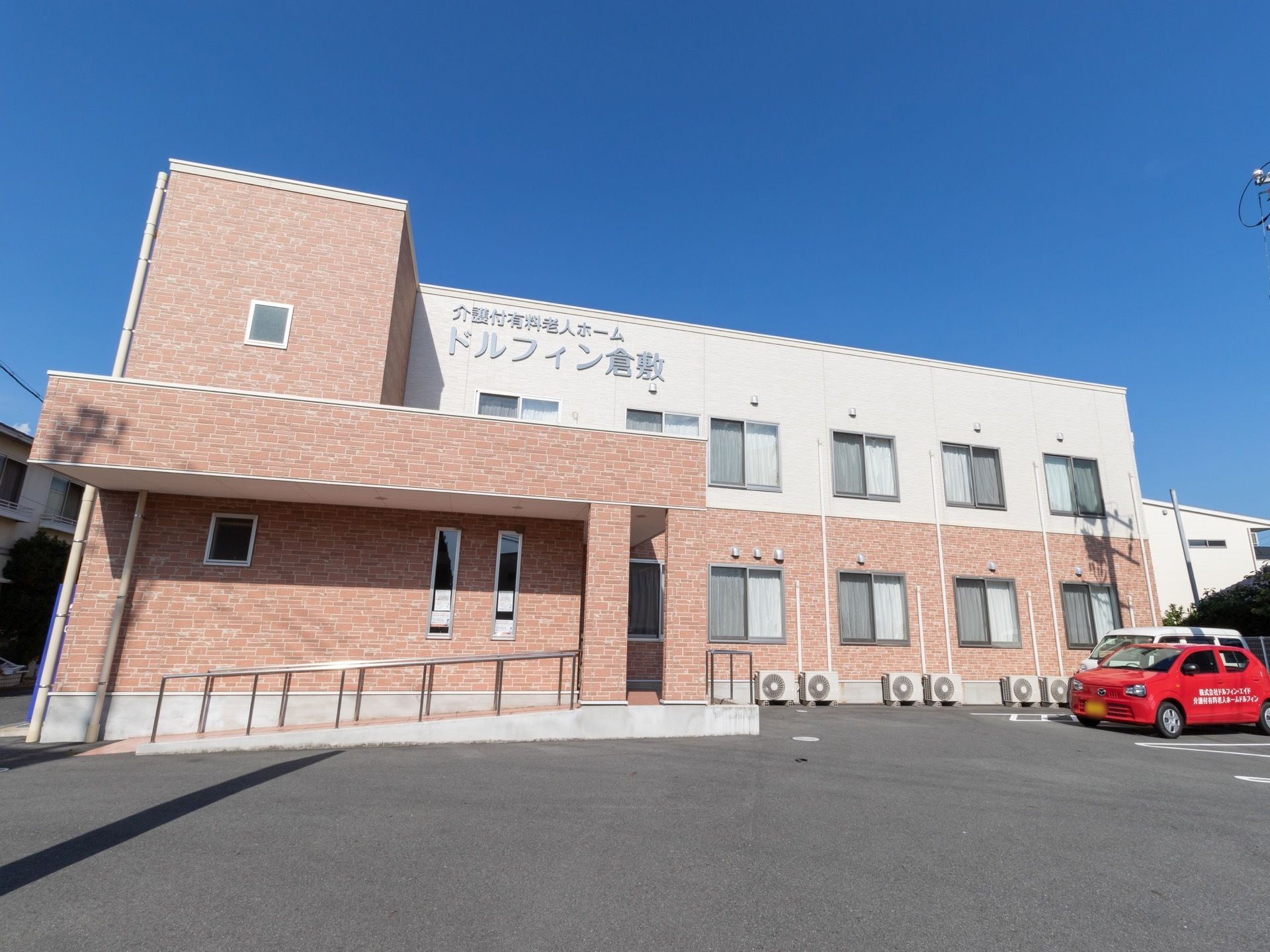 ２階建てのツートンカラーがスタイリッシュな外観の建物。白い外壁に、大きく目立つ文字で施設名が記載されている。