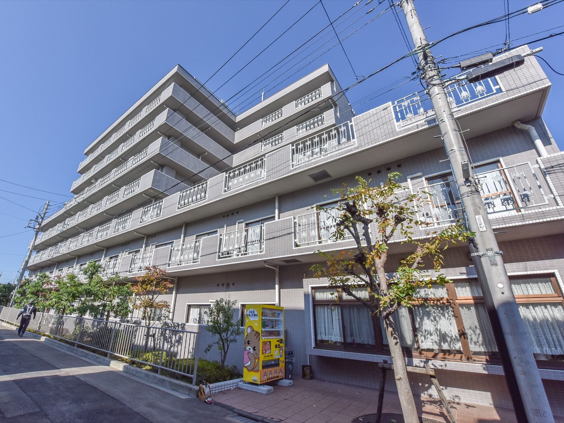 ７階建てとなっている施設は壁が全体的に灰色となっている。１階部分には黄色い色をした自動販売機が設置されている。