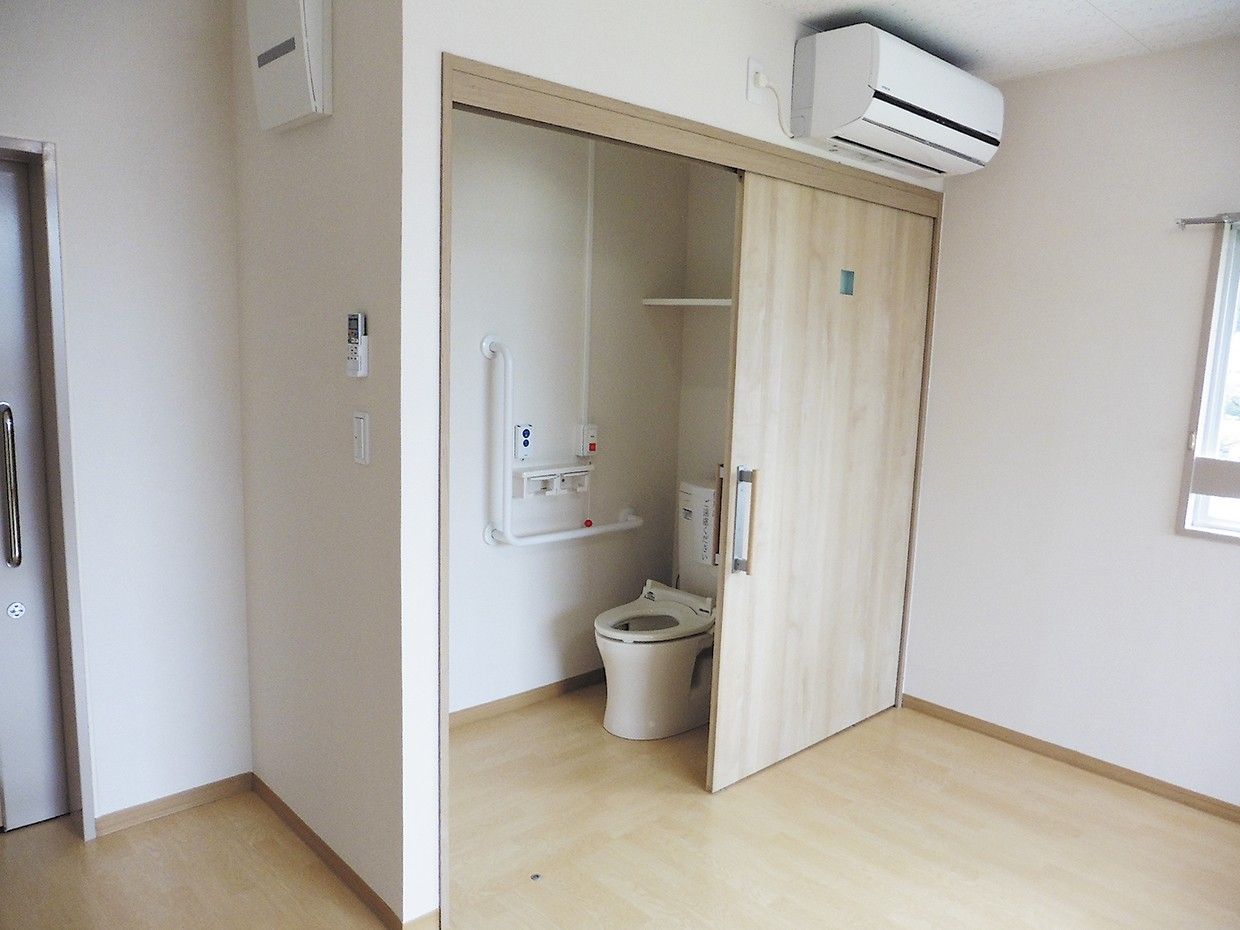 トイレの壁には手すりのほか、スタッフ呼び出し用のボタンなどが取り付けられている。また上部には、アメニティを置くための収納スペースがある。