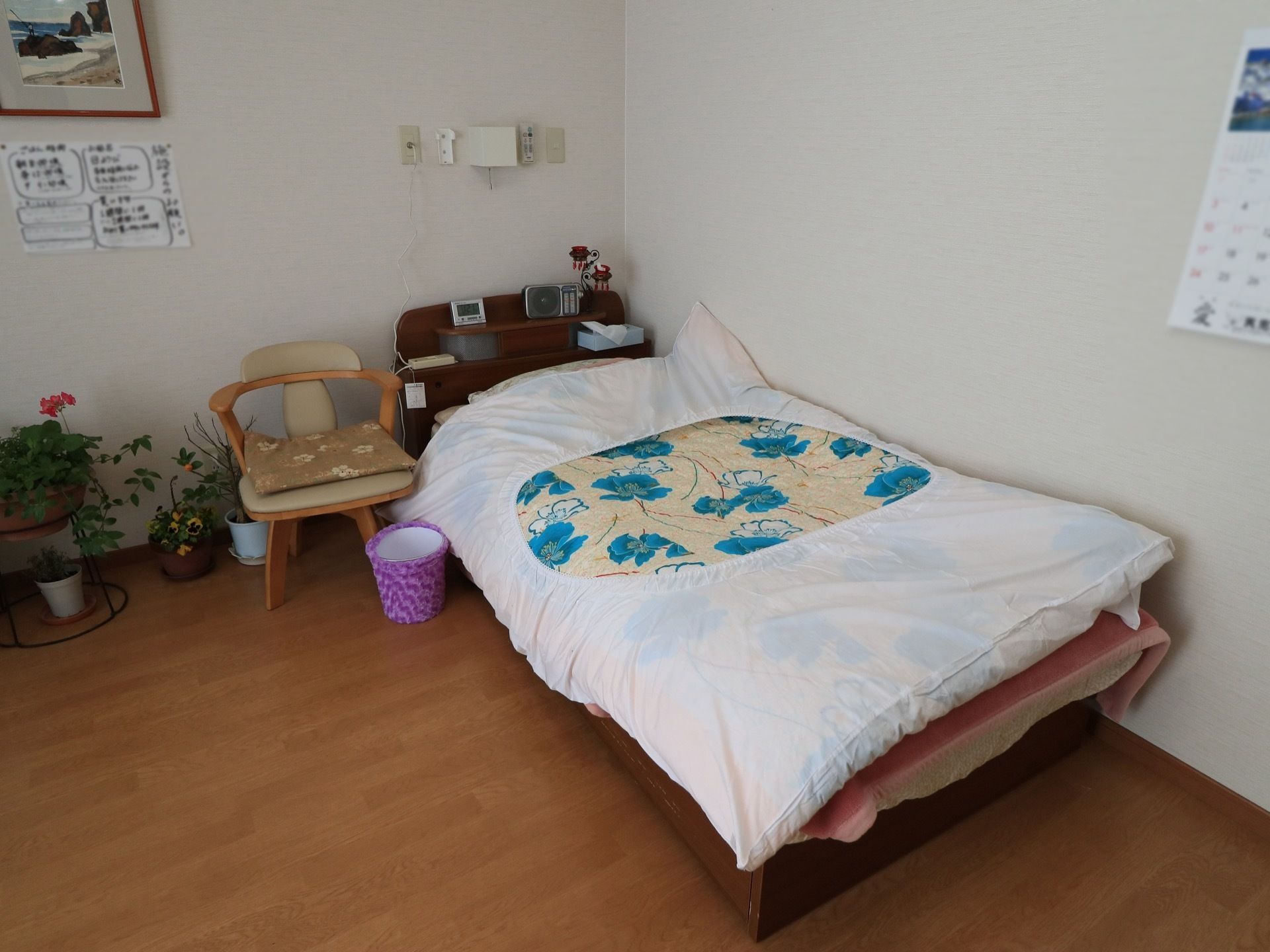 居室はフローリングタイプになっている。壁には白を採用し、明るい雰囲気になっている。壁際にベッドが置かれ、鉢植えの花が飾られている。