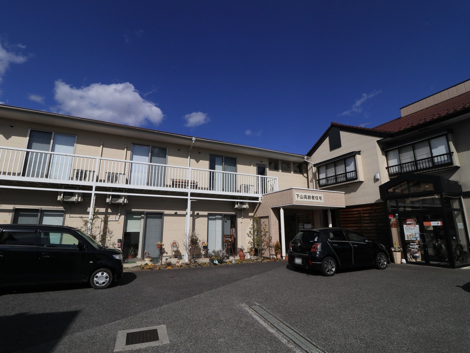 施設は広い敷地に2階建てで立地している。建物の前にはコンクリートで整備された駐車場が完備している。入口に屋根が設置されている。