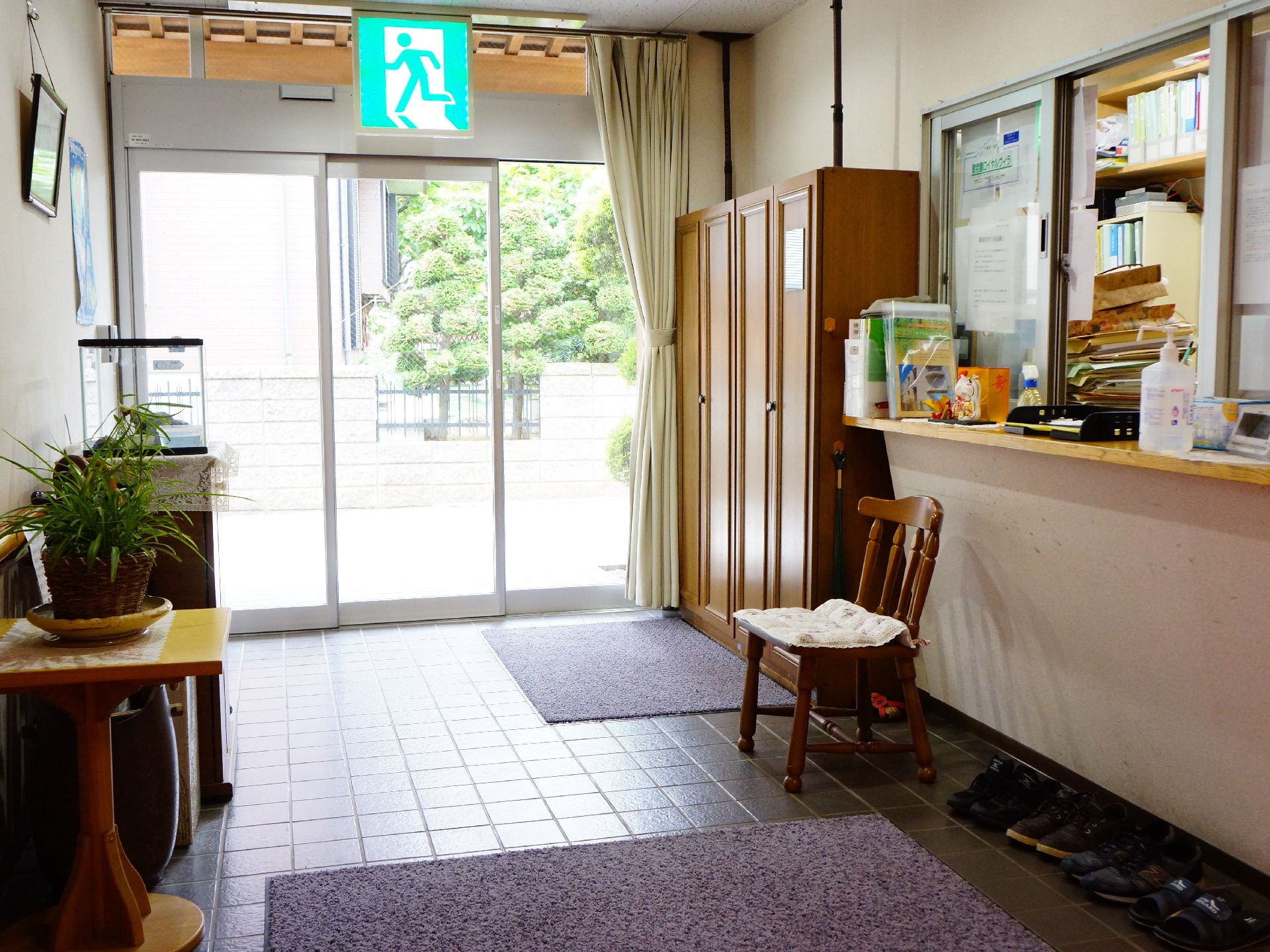 壁側に大きな下駄箱がある。その横には、座って靴が脱ぎ着できる椅子がおいてある。入るとすぐに事務室がある。