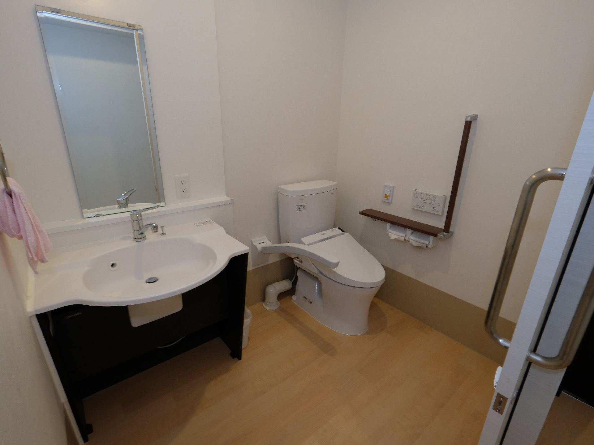 広々としたスペースがあるトイレには大きな鏡が取り付けられている洗面台が設置されている。便器の脇には手すり、緊急通報装置も設置されている。