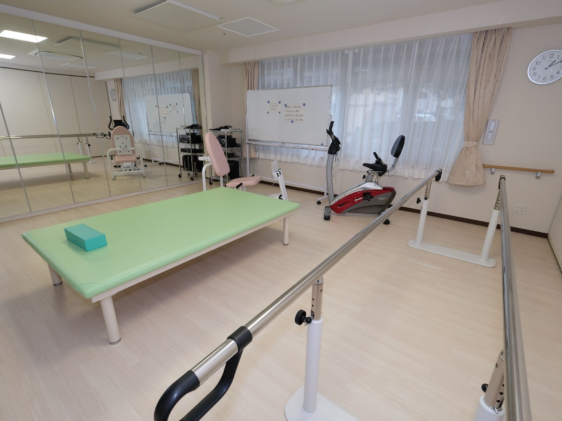 リハビリルームはフラットな床でバリアフリーとなっている。さまざまな介護用器具があり、壁一面には大きな鏡が取り付けられている。