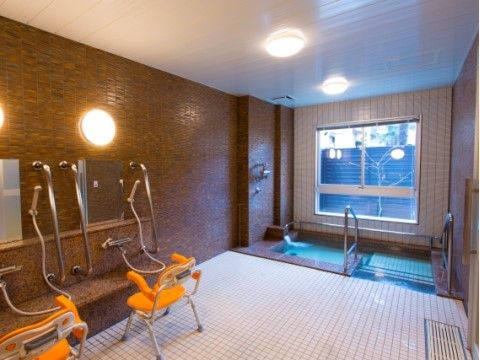 大浴場の窓は大きく、外を眺めながら入浴することができる。手すりやシャワーベンチなどが備え付けられているため、安心して入ることができる。