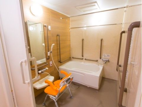 シャワーベンチが置いてある浴室。浴槽周りや鏡の周り、出入り口などに手すりが備え付けられているため、安心して入ることができる。