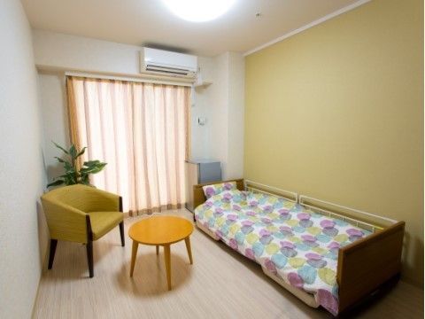明るい色の壁紙の居室には、ベッドやソファが置かれている。窓が大きく、光がたくさん入るため明るい部屋になっている。