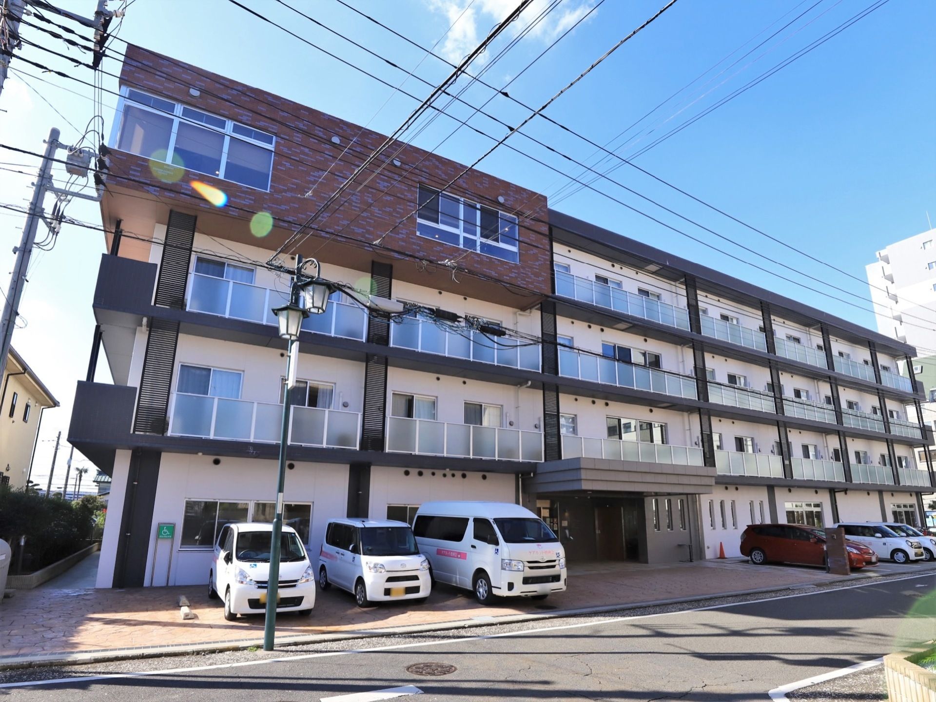 白と黒の２色で彩られたマンションが建っている。４階の一部分がレンガ調で、モダンなデザインとなっている。