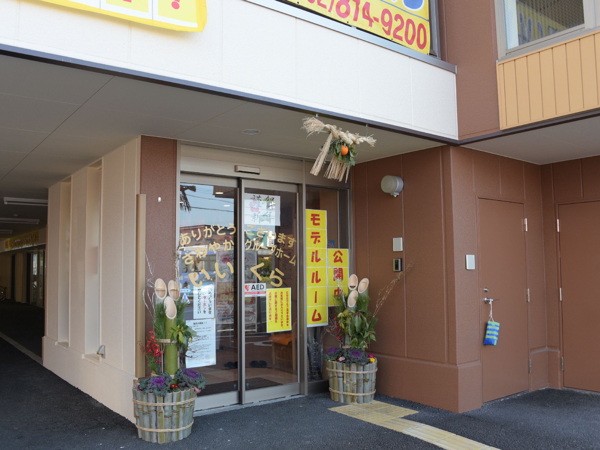 茶系と白を基調とした施設の入り口。アプローチはコンクリートできれいに整備され、バリアフリー対応になっている。