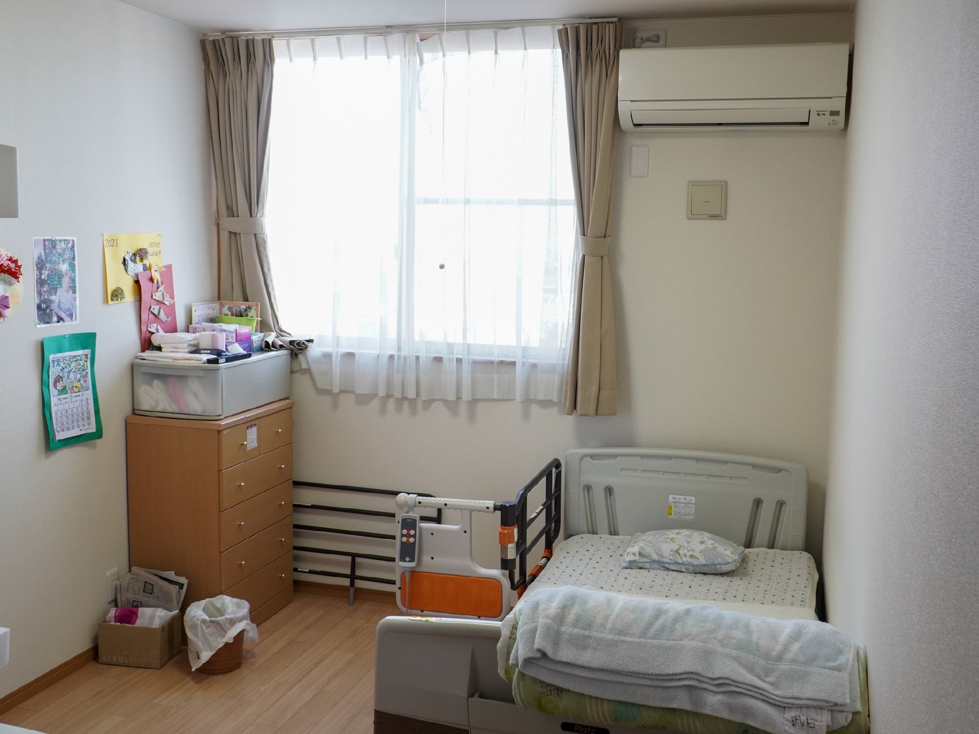 ベッドと木製の棚が置かれた白い壁の部屋