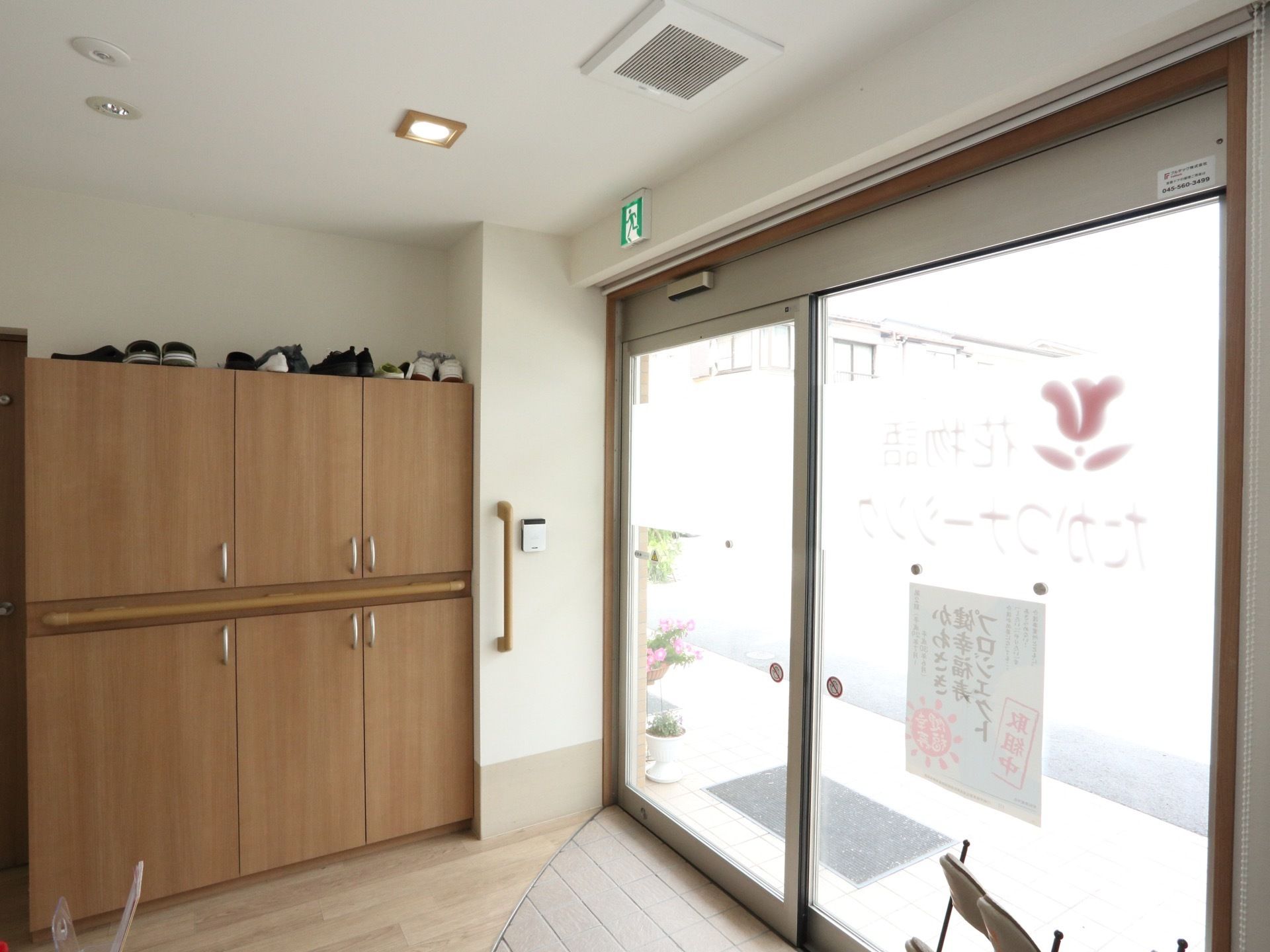 入り口横には花が飾られている。中に入ると収納とスリッパラックが設置されてあり、収納の上には靴が置かれている。