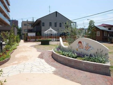 建物の手前には庭園が広がっている。洋風の東屋や、花壇の背面には天使の描かれた飾り壁があり、明るく柔らかな雰囲気がある。