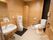 男性用便器、洋式便器、洗面台が設けられたトイレの個室である。壁には手すりが各所に設けられ、緊急時呼び出しベルも取りつけられている。