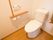 洋式のトイレの個室内である。壁に備わるトイレットペーパーホルダーの上には、小物を置くことができる棚がある。