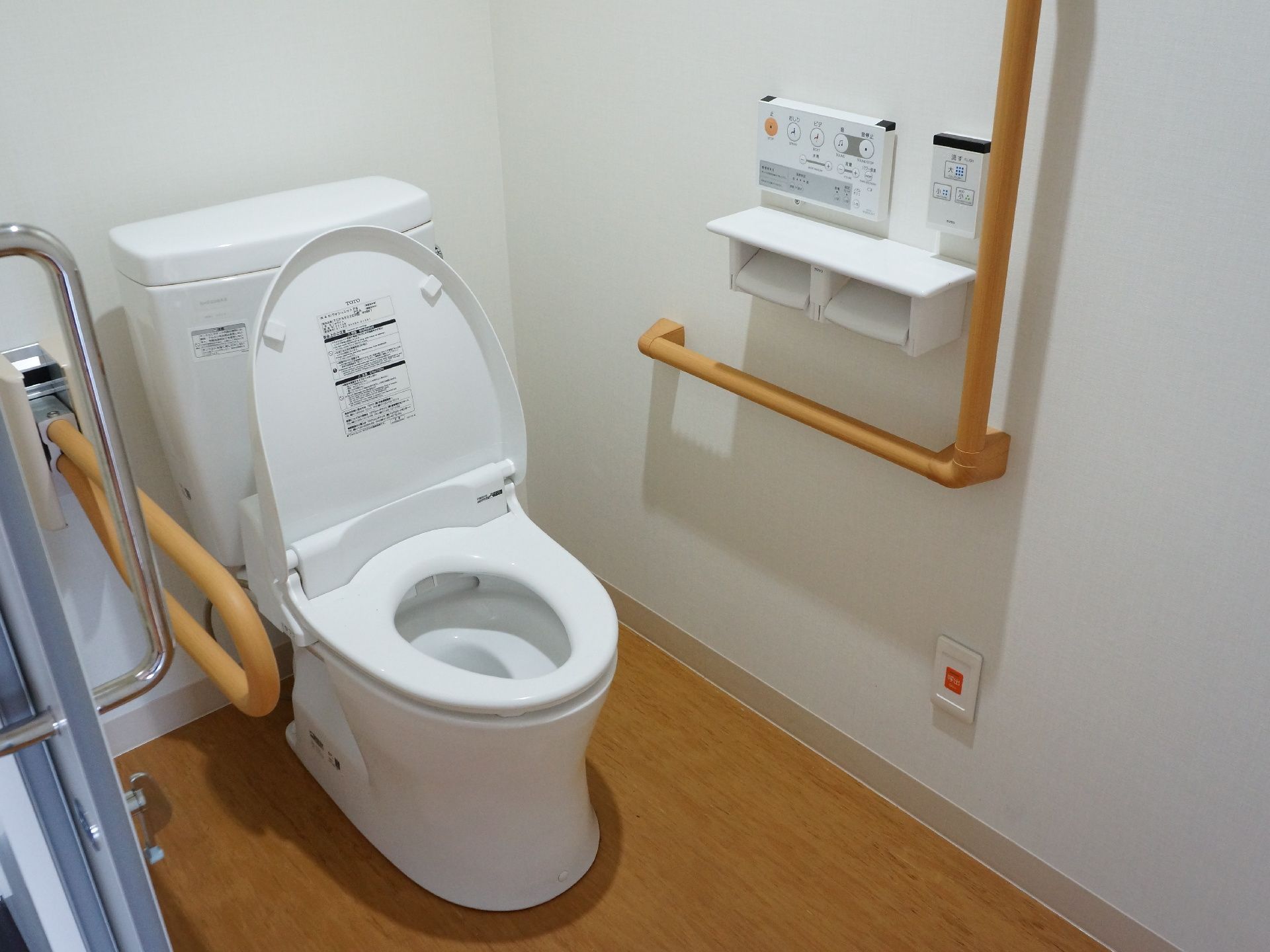 洋式トイレの便座横と壁側には形状の違う手すりが2つ取り付けられている。トイレットペーパーフォルダーも2つある。