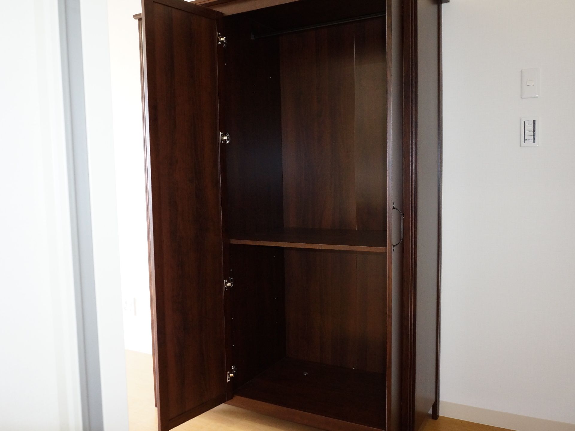 ある部屋にはダークブラウンのクローゼットが1台置かれている。中には仕切りが真ん中にあり、上下2つに分けて物を収納することができる。