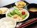 黒いお盆の上にはスプーンとお箸、ご飯やお味噌汁、メインのお肉などが置かれている。お肉は皮部分が取り除かれている。
