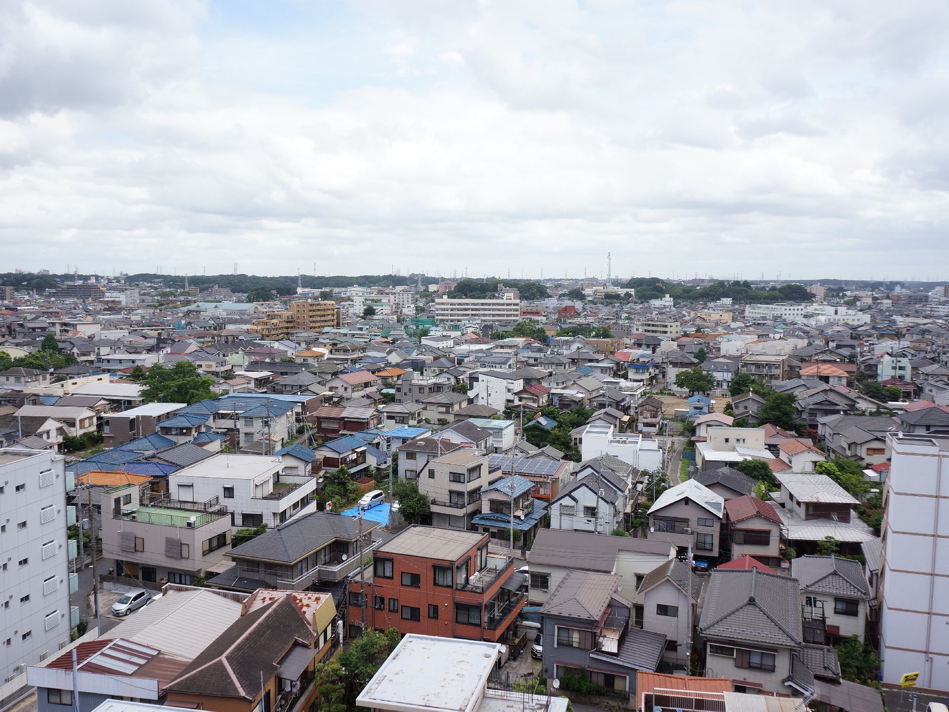 施設の屋上からは周りの景色が見渡せるようになっている。白色の屋根や青色の屋根の家やビルがたくさん立ち並んでいる。