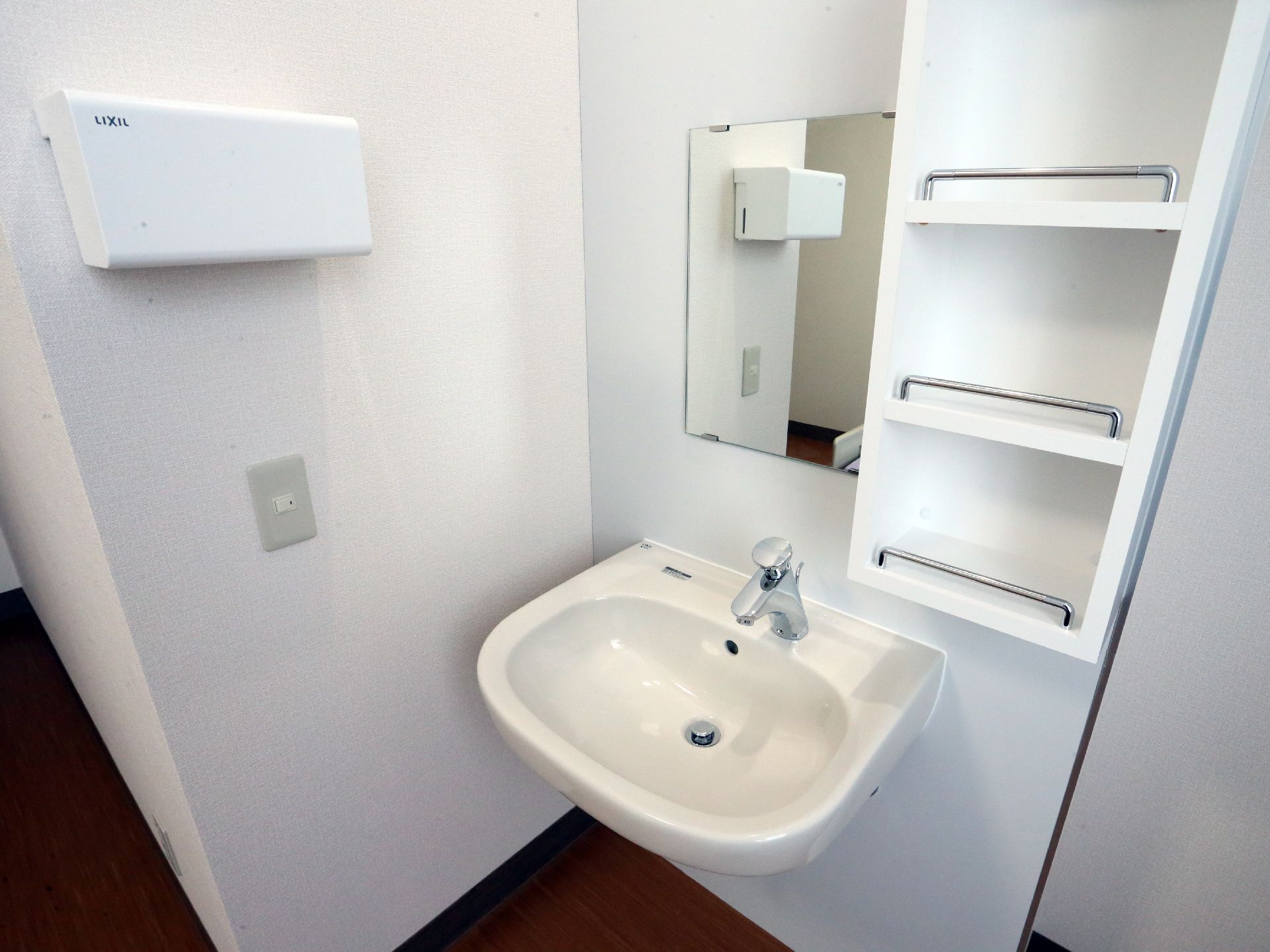 居室にはプッシュ式の蛇口のついた小さな洗面台が備え付けられている。手拭き用ペーパーを設置するボックスや鏡、小物を整理できる棚も備わっている。