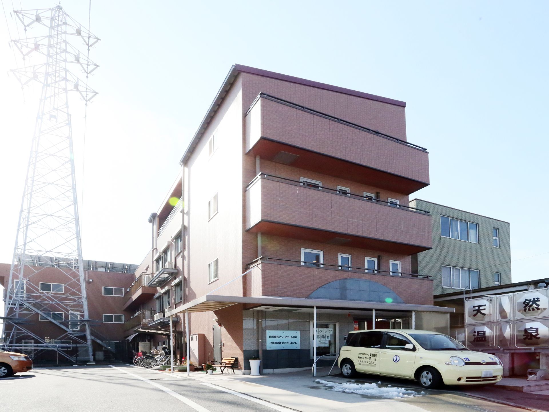 玄関の前あたりに「天然温泉」と書かれた大きなタンクがある。玄関前から横の一部に雨よけが付いており、ベンチが置いてある。